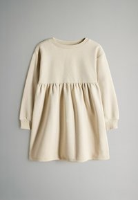 Vestido beige claro de tela suave, con mangas largas, escote redondo y cintura fruncida para una silueta fluida.