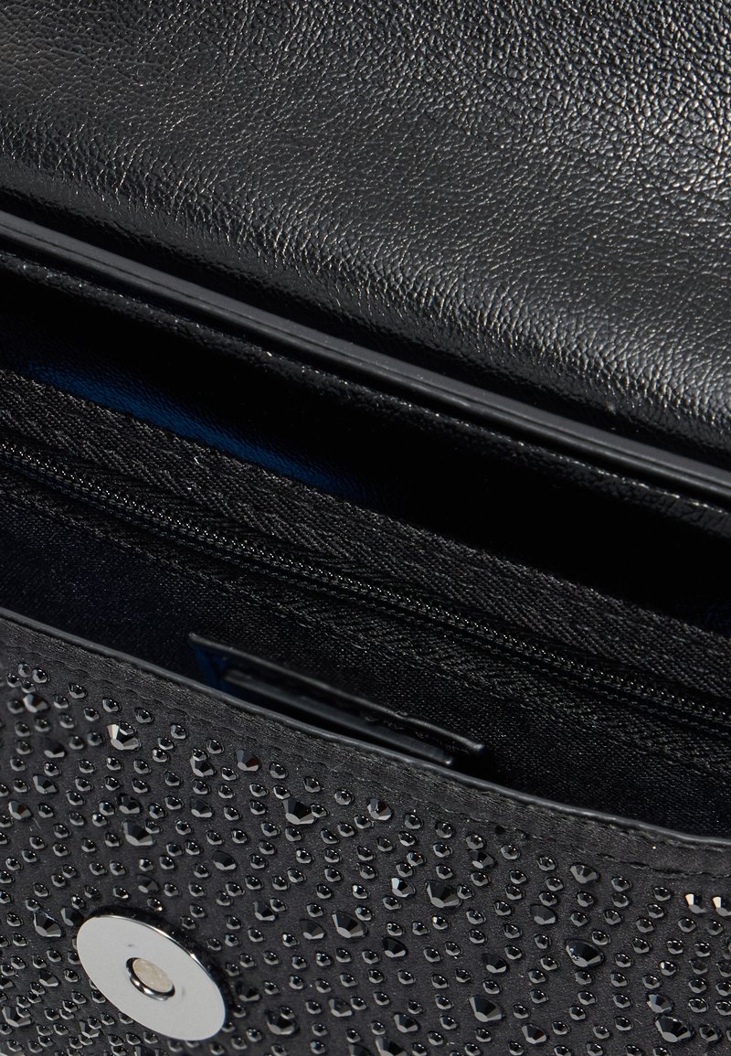 Borsa nera con texture, esterno liscio e dettagli a forma di perle in rilievo. L'interno presenta una tasca con zip e una fodera blu.