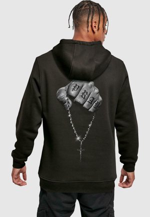 Black hoodie featuring a graphic of a clenched fist with "PRAY" tattooed on the knuckles, holding a rosary with a cross detail.