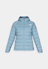 Light blue puffer jacket with a hood, featuring a zip closure, quilted texture, and logo accent on the upper left chest.