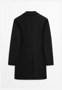 Black wool coat with a structured shape, long sleeves, and a notched collar. Features a single vent at the back and side pockets.