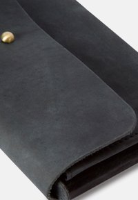 Black leather wallet with a smooth texture, a rounded shape, and a prominent brass snap closure. Folded edges create a clean design.