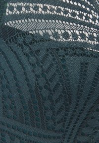 Tela de encaje verde profundo con intrincados patrones de formas geométricas y texturas elevadas, que exhibe finos detalles y delicada artesanía.