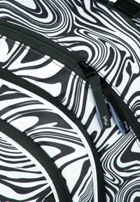 Zaino a pattern bianco e nero con un design ondulato, diversi compartimenti con zip e tessuto testurizzato con accessori neri.