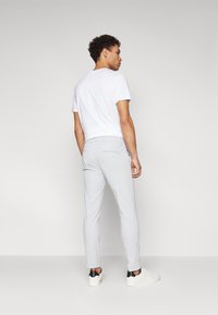 Világosszürke, slim fit chino nadrág, hátsó zsebekkel és közepes derékkal, sima fehér pólóval és fehér sportcipővel párosítva.