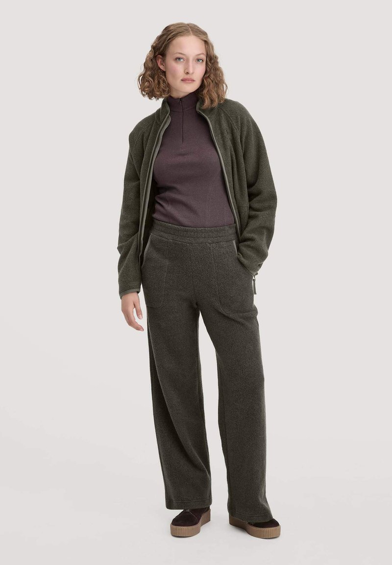 Fleece-Jacke in Dunkelgrün mit hohem Kragen, kombiniert mit passenden weit geschnittenen Hosen. Der Stoff hat eine weiche Textur und ist für höchsten Komfort designed.