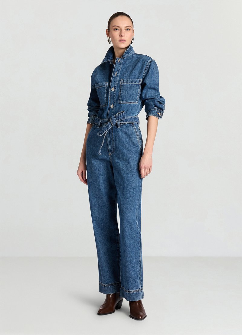 Denim-Overall in Mittelblau mit figurbetontem Oberteil, großen Taschen und langen Ärmeln. Verfügt über eine taillierte Passform mit Gürtel und weiten Hosenbeinen.