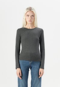 Grå langermet T-skjorte laget av ribbestrikket stoff, med rund hals og en tettsittende silhuett, sammen med blå jeans.