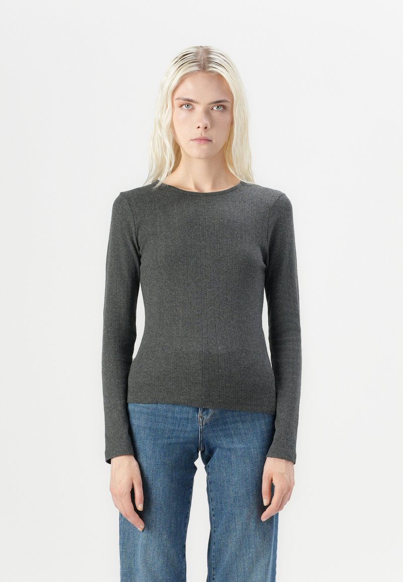 Grå langermet T-skjorte laget av ribbestrikket stoff, med rund hals og en tettsittende silhuett, sammen med blå jeans.
