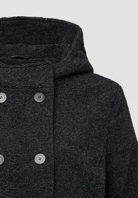 Zwarte gewatteerde jas met een textuurstof, dubbelgeknoopt ontwerp met twee metalen knopen, en een hoge kraag voor extra warmte.
