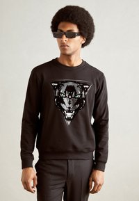 Sudadera negra con un gran diseño gráfico de la cara de un pantera con ojos verdes. Textura suave con puños y cuello acanalados.