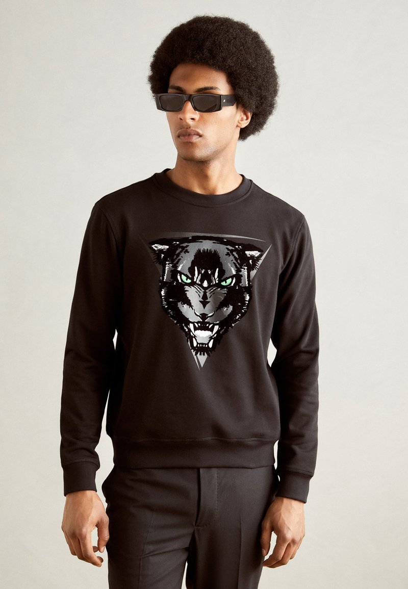 Sudadera negra con un gran diseño gráfico de la cara de un pantera con ojos verdes. Textura suave con puños y cuello acanalados.