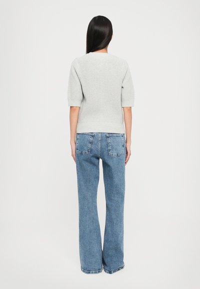 Grå strikkegenser med korte ermer, kombinert med lyseblå, høyt midje, utsvingte denimjeans. Teksturen har ribbestrikket mønster.