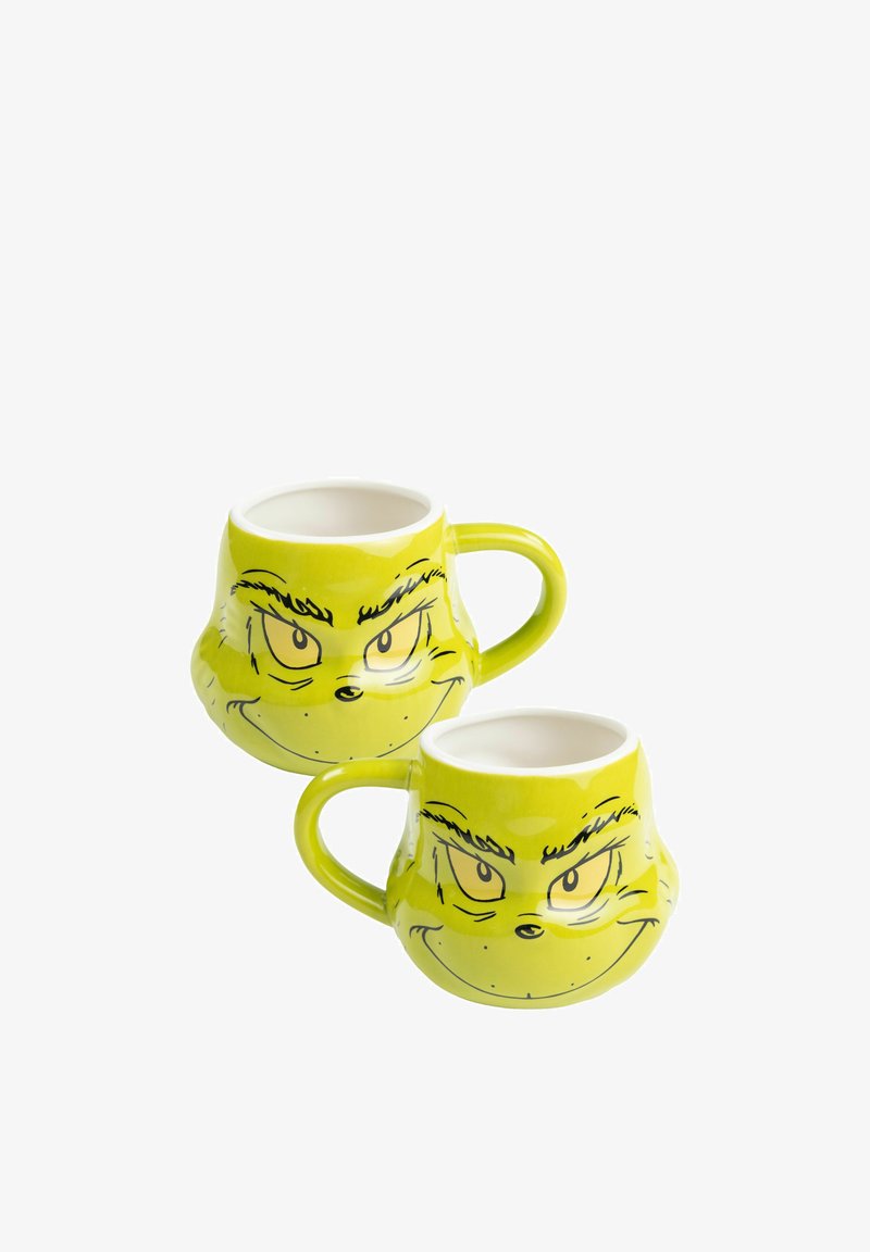 Green ceramic mugs featuring a facial design with a mischievous expression, rounded shape, and side handle; smooth, glossy finish.