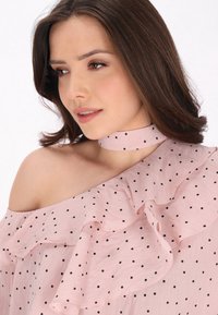 Rosa schulterfreie Bluse mit schwarzen Punkten, ausgestattet mit einem gerafften Kragen und einem passenden Choker mit Punkten. Weicher, leichter Stoff.
