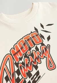 Cremfarbener Baumwoll-T-Shirt mit einem auffälligen rot-schwarzen Grafikdruck und dem Text "MOTO Racing" sowie karierten Musterelementen.