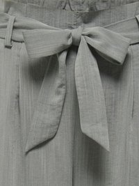 Sivý látkový opasok zviazaný do mašle v páse k zodpovedajúcim nohaviciam s vysokým pásom, opaskovými pútkami a jemnými vertikálnymi pruhmi.