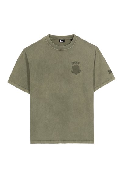 Camiseta de algodón verde oliva con mangas cortas, cuello redondo acanalado y un emblema texturizado en el lado izquierdo del pecho, que presenta un diseño de insignia.