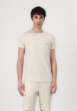 Tricou bej din bumbac, cu guler rotund, mânecă scurtă și un mic logo pe piept. Asortat cu șorturi cargo bej.