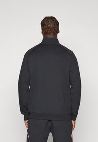 Zwarte rits sweatshirt met hoge kraag, textuurstof, slim fit, contrasterende schouderaccenten en zijzakken.