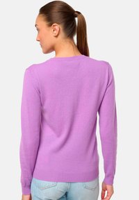 Pull long à manches longues lilas avec un col rond, texture douce, ourlet côtelé et épaules sans couture, associé à un jean bleu clair.