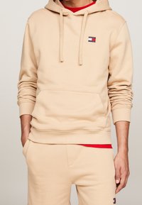 Beige Kapuzenpullover aus Baumwollmischung, mit einer Fronttasche, Kordeln und einem kleinen Logopatch auf der Brust. Geschmeidige Textur und lockere Passform.