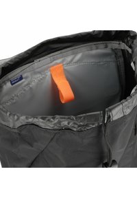 Mochila negra impermeable, con un tirador naranja en el interior, exterior de nailon y cierre de cordón. Forro gris suave.
