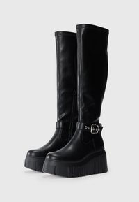 Black knee-high boots made from smooth leather, featuring a platform sole, side zipper, and ankle strap with buckle detail.