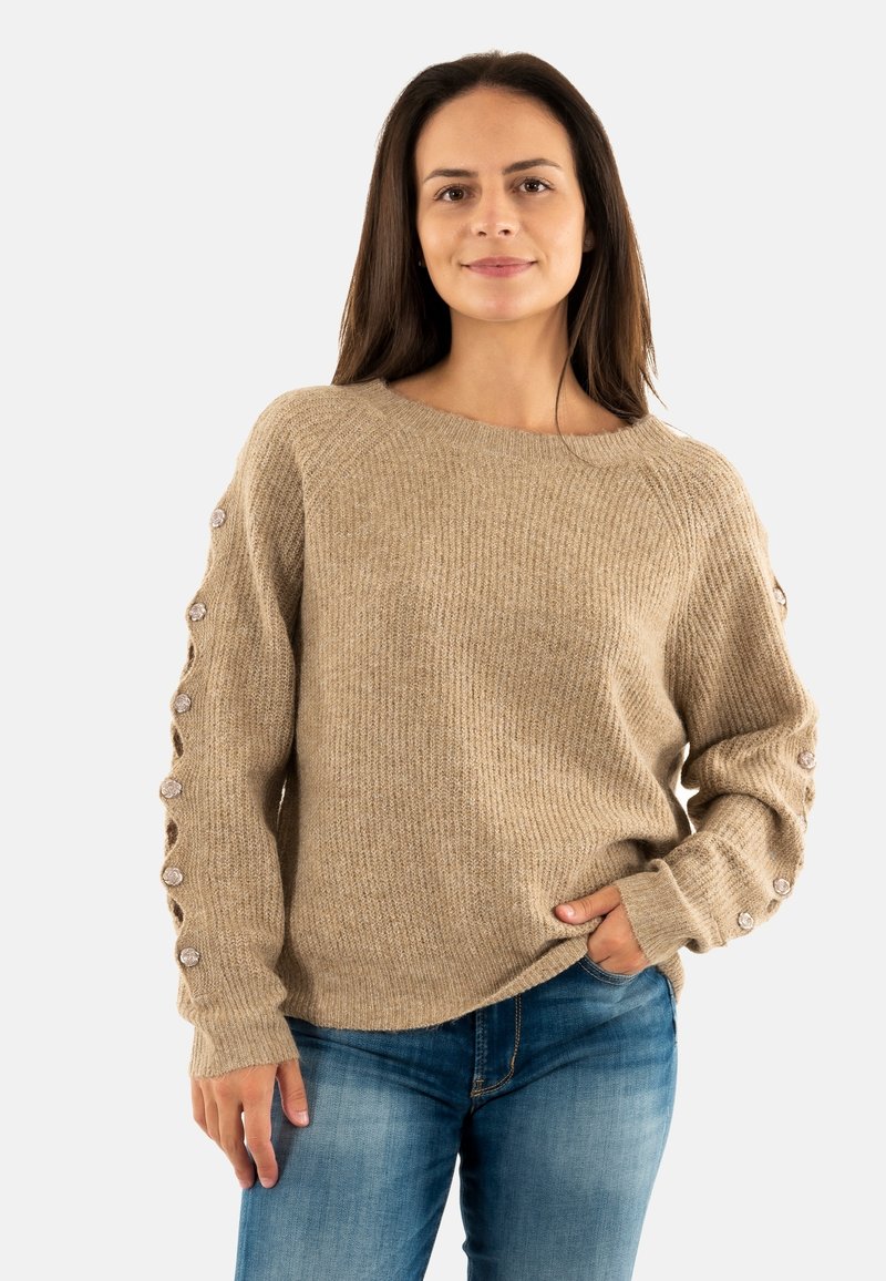 Maglione beige con texture a coste, dotato di una scollatura ampia e maniche lunghe con bottoni decorativi lungo i lati.