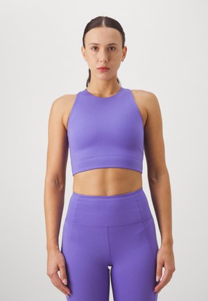 Violetti urheilu crop-top ja korkeavyötäröiset leggingsit sileästä, joustavasta kankaasta. Suunnittelussa on urheilullinen takaosa ja istuva muotoilu.