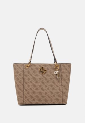 Sac cabas beige avec logos brun foncé à motifs, ferrures dorées, deux bretelles et breloques décoratives suspendues sur le côté droit.