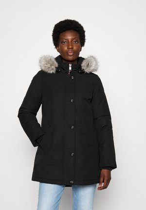 Cappotto imbottito nero con cappuccio e bordo in pelliccia sintetica, bottoni frontali e tasche laterali. Tessuto morbido, vestibilità regolare e maniche lunghe.