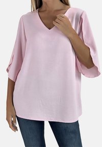 Lichtroze, loszittende blouse met een V-hals en brede, vloeiende mouwen. Gemaakt van een gladde stof met een subtiele textuur.