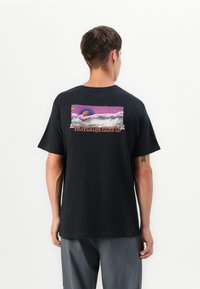Zwarte katoenen t-shirt met een kleurrijk grafisch ontwerp van wolken en hemelse elementen op de achterkant, met de tekst "Smaakt als de Hemel."