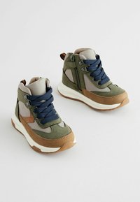 Baskets montantes en vert olive et taupe, avec des lacets navy, des panneaux en maille et des accents en suède marron. Fermeture à double zip et lacets.