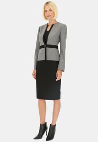 Szary żakiet z czarnymi akcentami, dopasowany krój, w połączeniu z czarną spódnicą ołówkową. Uzupełniony eleganckimi czarnymi botkami na kostkę.