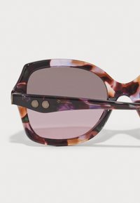 Lunettes de soleil surdimensionnées avec une monture en acétate multicolore ornée de motifs violets et oranges. Verres teintés foncés avec des accents en métal ronds.
