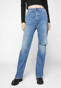 Jeans de cintura alta em azul claro, com corte reto, apresentando detalhes desgastados e fecho de botão. O material é denim com uma textura suave.