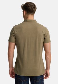 Olivengrøn polo-shirt med klassisk krave, korte ærmer og lige kant. Fremstillet af blødt bomuld med en glat overflade.