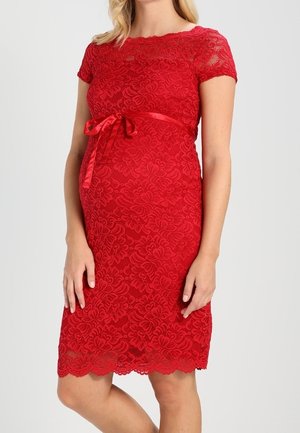 Vestido de maternidad rojo de encaje con mangas cortas, dobladillo con borde festoneado, patrón floral y cinturón de satén atado en un lazo. Diseño texturizado y ajustado.