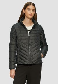 Schwarze, isolierte Steppjacke mit diagonalen Nähten, hohem Kragen und Reißverschluss. Verfügt über seitliche Taschen und eine glatte, glänzende Textur.