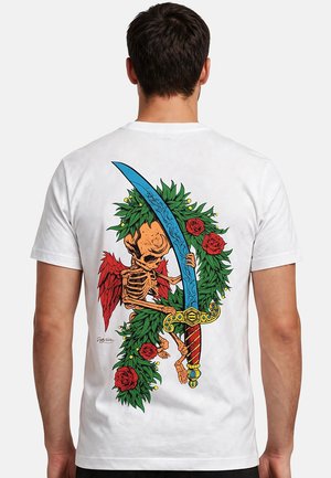 Hombre con camiseta blanca con diseño colorido en la espalda de un esqueleto con alas rojas sosteniendo una espada azul, rodeado de hojas verdes y rosas rojas.