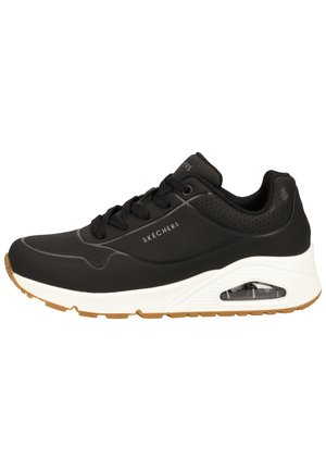 Baskets Skechers noires avec détails perforés, semelle blanche épaisse avec coussin d'air visible et semelle marron, vue de côté.