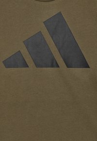 Olivengrønn bomulls T-skjorte med en stor svart tre-stripes logo på forsiden. Glatt tekstur med rund hals.