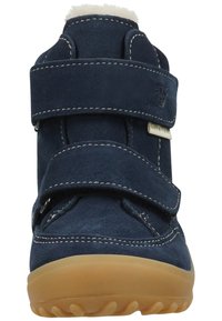 Zapatilla alta de ante azul marino con dos correas de Velcro ajustables, suela de goma marrón y borde de piel blanca en el cuello. Detalles de costura visibles.