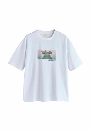 Fehér rövid ujjú póló, melyen egy nyomtatott fénykép látható egy fából készült mólóról, amely a víz fölé nyúlik, és két ember ül a végén hajnalban.