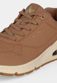 Кафяв маратонка Skechers с мрежести детайли, бежова подметка и връзки, с лого на Skechers отстрани и на езика.