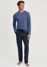 Langopenblauwe top met ronde hals, gecombineerd met marineblauwe gestreepte broek met geometrische vormen en een trekkoord in de taille.