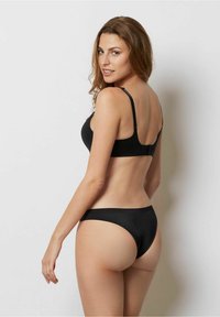 Svart bikini-set med en slät, sömlös design. Tyget är mjukt med justerbara remmar och minimalistisk klippning för komfort.