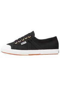 Schwarze Canvas-Sneaker verfügen über eine weiße Gummispitze, goldene Ösen und eine braune Gummisohle mit strukturiertem Grip. Logo an der Seite sichtbar.